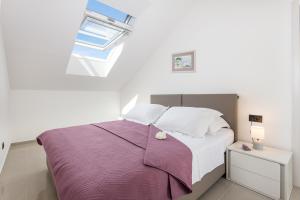 a bedroom with a bed with purple sheets and a window at Apartments Marando in Dubrovnik
