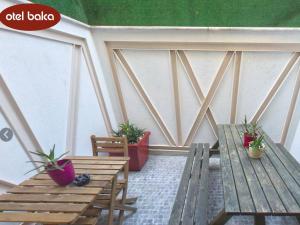 イズミールにあるHotel Balcaの木製ベンチ2台と鉢植えの植物が備わるバルコニー