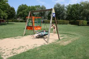 two people playing on a swing set in a park at Camping Aux Rives du Soleil in Pont-de-Vaux