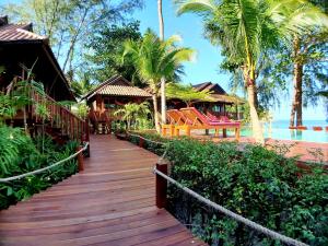 a wooden walkway leading to a resort with palm trees at Salad Hut in Salad Beach