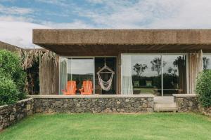 two orange chairs sitting on a porch with windows at Santa Barbara Eco-Beach Resort in Ribeira Grande