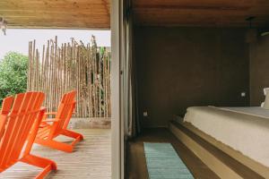 a bedroom with a bed and a chair on a porch at Santa Barbara Eco-Beach Resort in Ribeira Grande