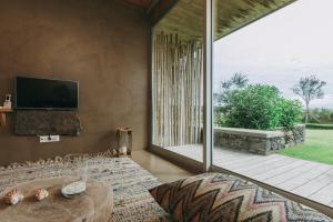 a living room with a tv and a large window at Santa Barbara Eco-Beach Resort in Ribeira Grande