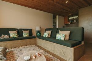 a living room with a green couch with pillows at Santa Barbara Eco-Beach Resort in Ribeira Grande