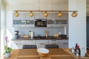 a kitchen with white cabinets and a wooden table at Penthouse am Meer Barth in Barth