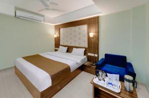 een slaapkamer met een bed en een blauwe stoel bij HOTEL SHITAL INN in Ahmedabad