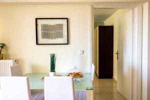 a dining room with a glass table and white chairs at Irini Apartments in Kavála
