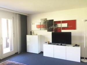 una sala de estar con TV en un armario blanco en Disentiserhof C502, en Disentis
