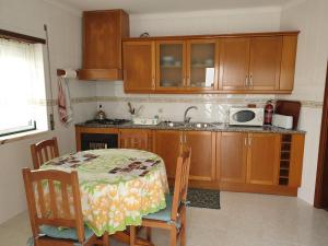 Una cocina con gabinetes de madera y una mesa con sillas. en HOMELIDAYS CLARA NAZARE, en Nazaré 10 fotos más