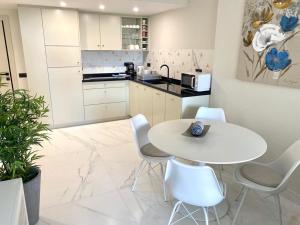 cocina blanca con mesa blanca y sillas en Apartment APOLO XIV en Calpe