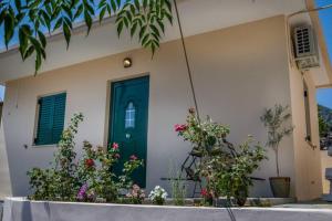 dom z zielonymi drzwiami i kwiatami w obiekcie Blanca Serenidad Luxury Apartment w mieście Methana