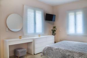 ein Schlafzimmer mit einem Bett, einem Spiegel und einer Kommode in der Unterkunft Blanca Serenidad Luxury Apartment in Methana