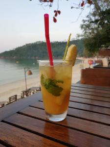 uma bebida com uma palha vermelha sentada numa mesa ao lado da praia em Salad Hut em Salad Beach