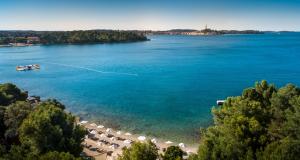 a view of a beach with a boat in the water at Maistra Select Family Hotel Amarin in Rovinj