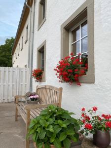 eine Holzbank vor einem Gebäude mit roten Blumen in der Unterkunft An der Walnuss in Feilsdorf