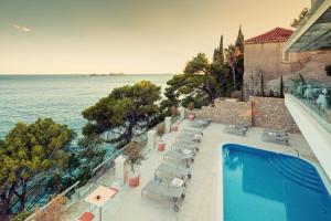
a beach with a pool and a balcony overlooking the ocean at Hotel More in Dubrovnik
