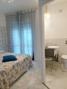 a bedroom with a bed and a bathroom with a sink at Acquamarina Apartment with Terrace in Marsala