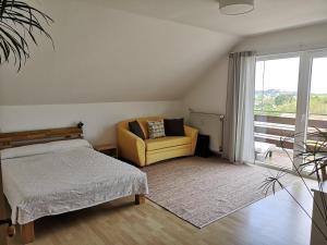 a bedroom with a bed and a couch and a window at Ferienwohnung "Weinbergblick" im Winzerdorf in Leinsweiler