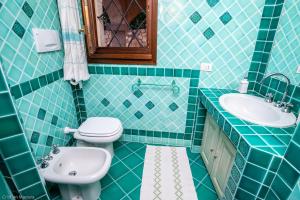 a blue tiled bathroom with a toilet and a sink at villa smeralda in Cannigione