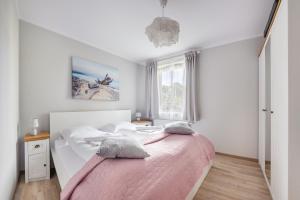 - une chambre avec un lit et une couverture rose dans l'établissement Apartamenty Sun & Snow Rezydencja Park, à Mielno