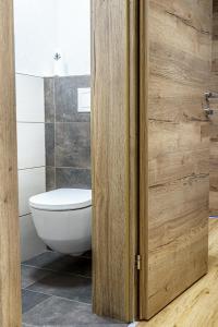 a bathroom with a toilet and a wooden door at Haus Löger Apartments Pyhrn Priel in Windischgarsten