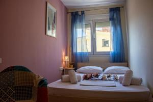 a bedroom with a bed with blue curtains and a window at Irini Apartments in Kavála