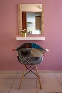 a chair in front of a pink wall with a mirror at Irini Apartments in Kavála
