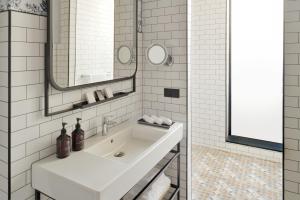 a white bathroom with a sink and a mirror at Mövenpick Hotel The Hague in The Hague