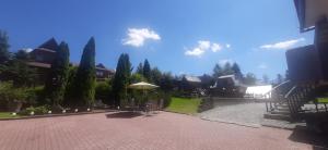 a courtyard with tables and an umbrella and trees at U Białasów in Małe Ciche