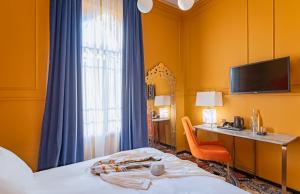Cette chambre comprend un lit, un bureau et une télévision. dans l'établissement Villa Brown Moshava - a member of Brown Hotels, à Jérusalem