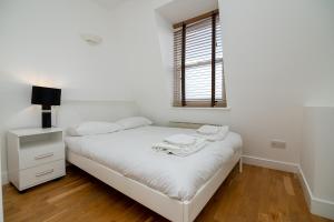 a white bedroom with a bed and a window at Modern 1 Bed Flat for up to 2 people in Holborn, London with free wifi in London