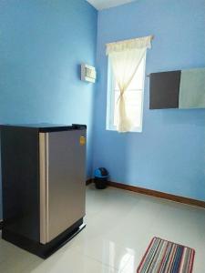 Cette chambre bleue dispose d'un réfrigérateur et d'une fenêtre. dans l'établissement Ariya Garden Home, à Chumpon