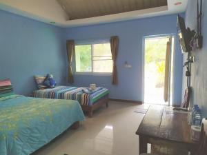 1 dormitorio con paredes azules, 1 cama y 1 mesa en Ariya Garden Home en Chumphon