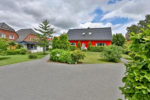 ein rotes Haus mit einem schwarzen Dach und einer Auffahrt in der Unterkunft Ferienhäuser Fuchsweg in Stralsund