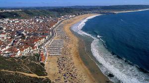 una vista aérea de una playa y el océano en HOMELIDAYS CLARA NAZARE, en Nazaré