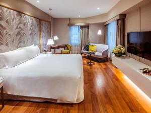 a bedroom with a large white bed and a living room at Manto Hotel Lima - MGallery in Lima