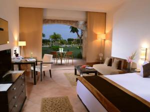 um quarto de hotel com uma cama e uma sala de estar em Mövenpick Resort El Sokhna em Ain Sokhna