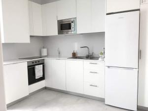 Biała kuchnia z białymi szafkami i kuchenką mikrofalową w obiekcie Casita cerca de la playa decorada con amor w mieście Tarifa