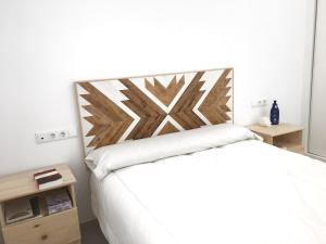 sypialnia z białym łóżkiem z drewnianym zagłówkiem w obiekcie Casita cerca de la playa decorada con amor w mieście Tarifa