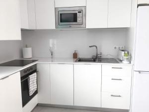 biała kuchnia ze zlewem i kuchenką mikrofalową w obiekcie Casita cerca de la playa decorada con amor w mieście Tarifa +7 zdjęć