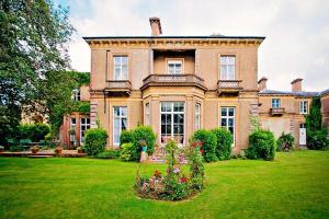 uma casa grande com um jardim verde com flores em Albert Cottage Hotel em East Cowes