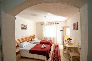Habitación con 2 camas, mesa y escritorio. en Guest House Garden, en Gjirokastra
