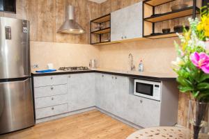 a kitchen with stainless steel appliances and wooden cabinets at Lux apartment on Nezalezhnoi Ukrаiny 39-B near Bulvar Shevchenko in Zaporozhye