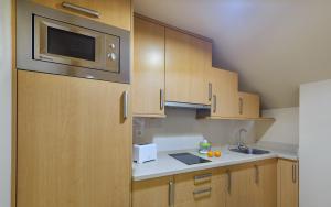 cocina con armarios de madera y microondas en Apartamentos Trisquel, en Sanxenxo