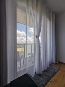 a room with white curtains and a view of a balcony at Biała Perła Apartment in Gdańsk