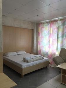 a bedroom with a bed and curtains and a couch at Ryabinka Hotel in Cheboksary