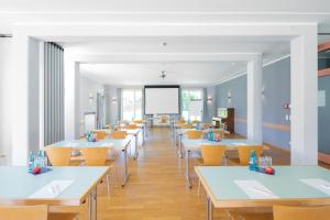 eine Cafeteria mit Tischen, Stühlen und einem Whiteboard in der Unterkunft JUFA Hotel Nördlingen in Nördlingen