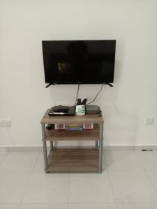 una mesa pequeña con TV en la pared en Ros Residence, en Ayer Keroh