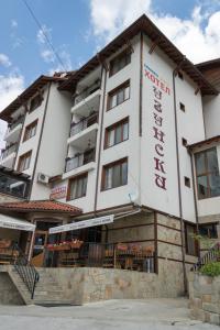 a large white building with tables and chairs in front of it at Hotel Uzunski in Smolyan
