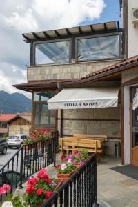 a restaurant with a bench and an awning and flowers at Hotel Uzunski in Smolyan